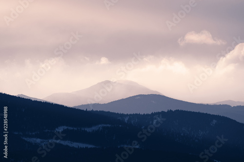 Dramatic winter storm blows over a cold barren landscape at sunset