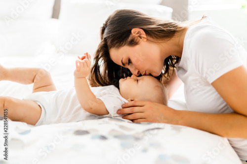 mother with baby on bed having good time