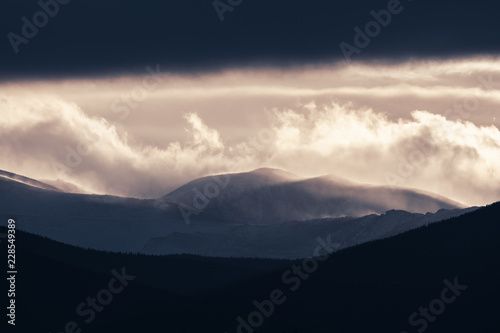 Dramatic winter storm blows over a cold barren landscape at sunset