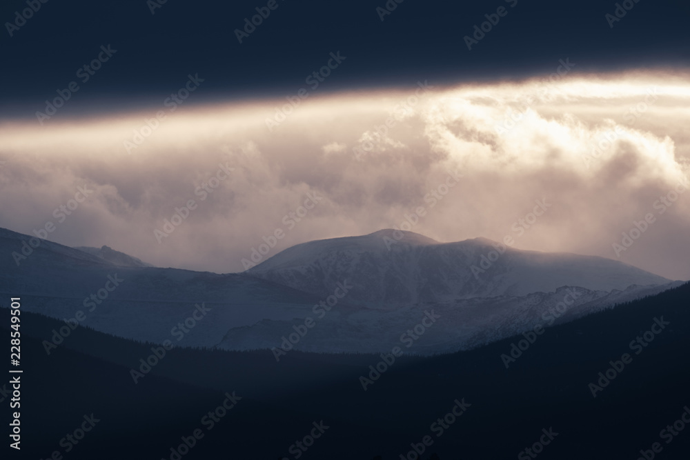 Dramatic winter storm blows over a cold barren landscape at sunset