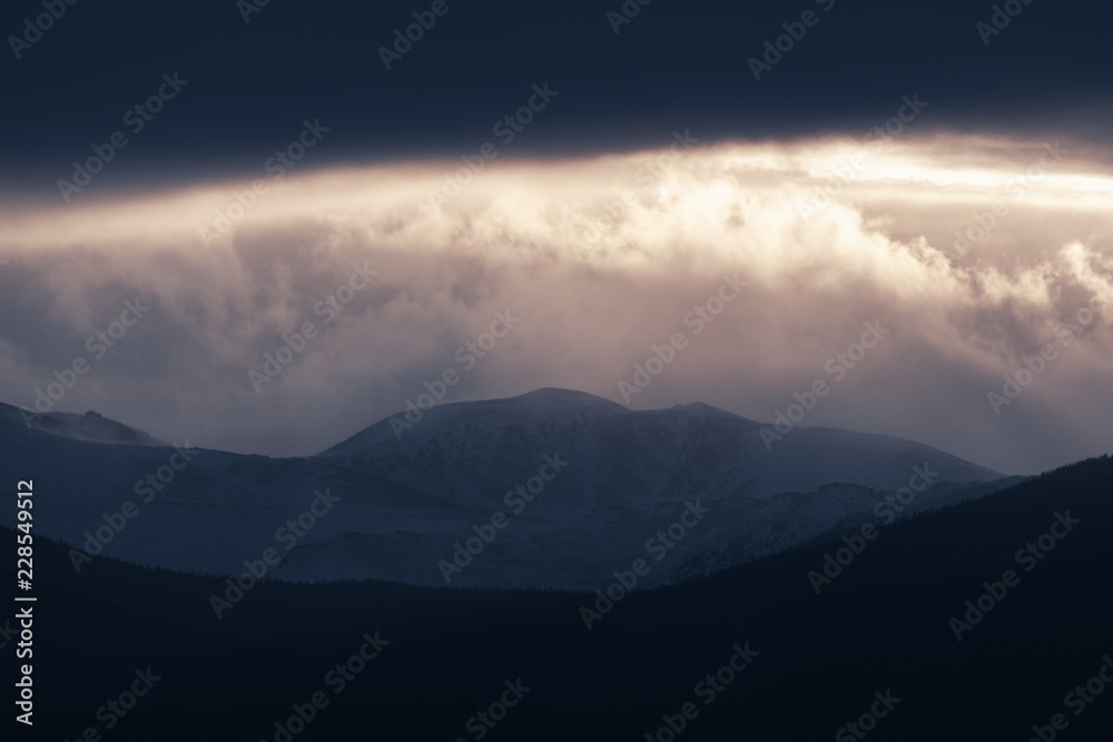 Dramatic winter storm blows over a cold barren landscape at sunset