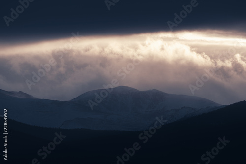 Dramatic winter storm blows over a cold barren landscape at sunset