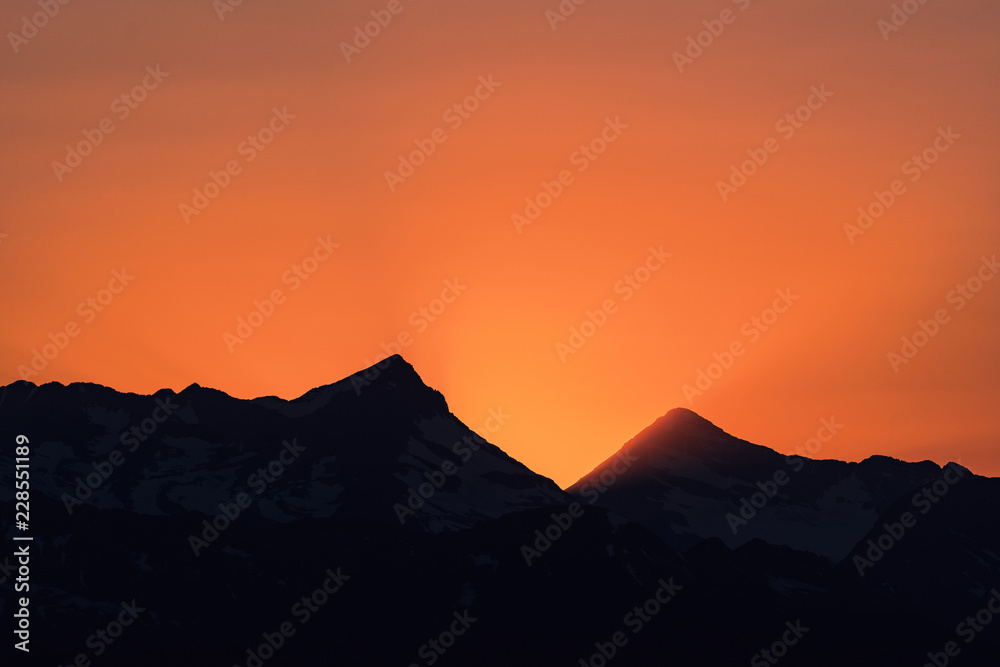 Dramatic sun rays as the sun sets behind Heaven's Peak and Livingston Range, in Glacier National Park, Montana