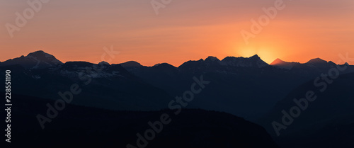Panorama of Dramatic sun rays as the sun sets behind Heaven's Peak and Livingston Range, in Glacier National Park, Montana