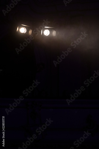 Two white stage lights in a dark environment