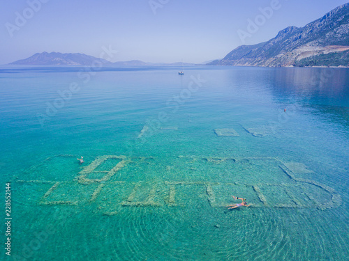 Aerial drone bird's eye view photo of tourists snorkeling above old Sunken City of Epidauros, Greece photo