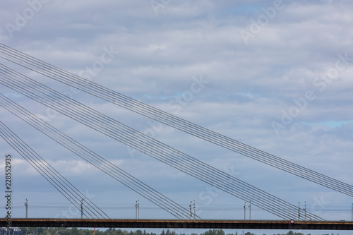 A part of a bridge with wires on a cloudy background