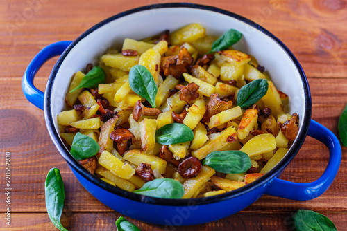 Fried potatoes with chanterelle mushrooms on a wooden table. Traditional Russian dish