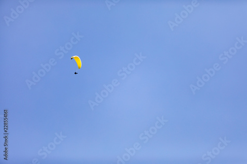 A person with a parachute up in the air on a blue sky