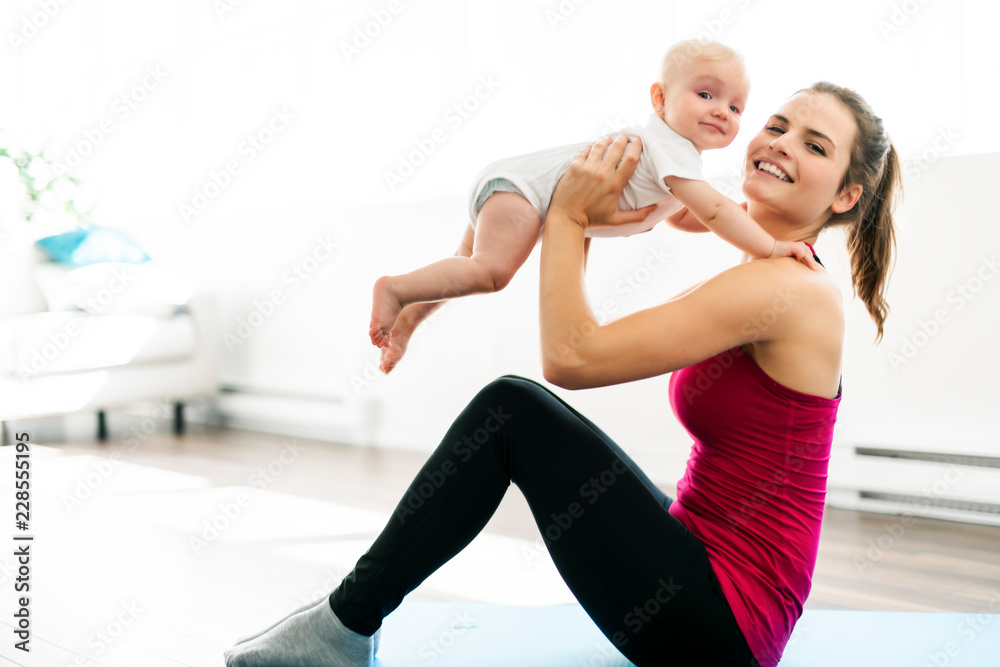 A Portrait of beautiful young mother in sports wear with her charming little baby in training session A Portrait of beautiful young mother in sports wear with her charming little baby in training session