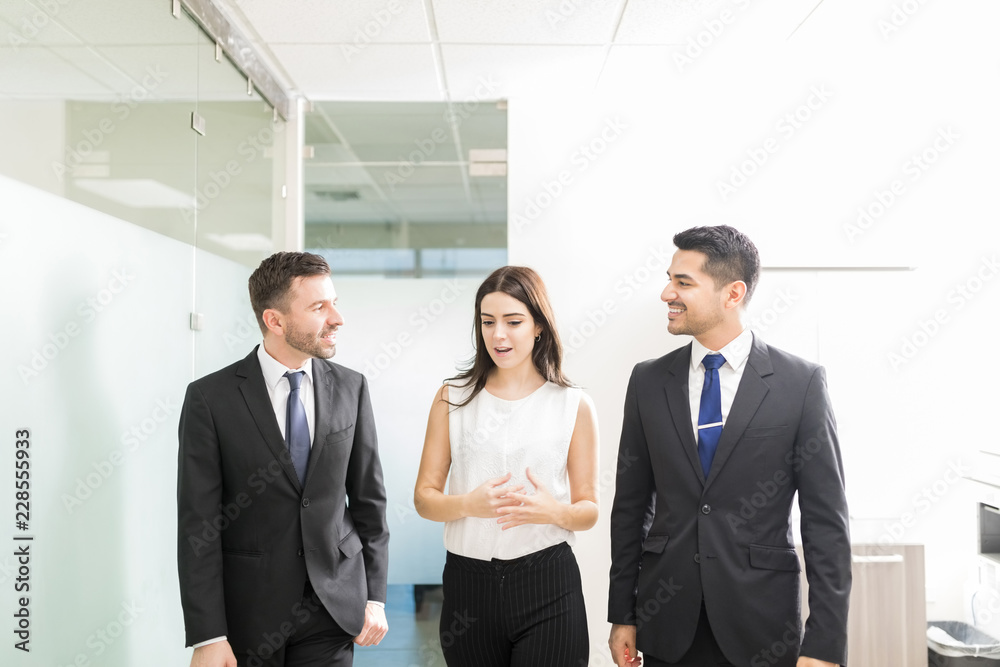 Business People Discussing While Walking Together In Office Business People Discussing While Walking Together In Office