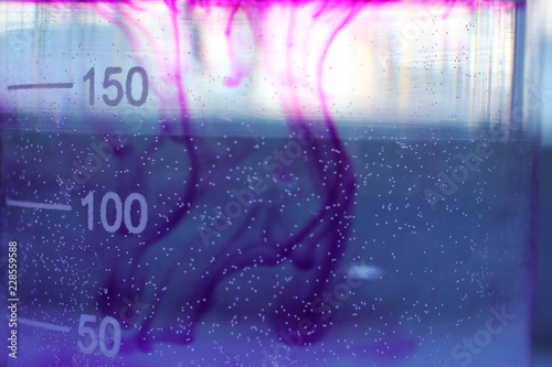 The process of dissolving a purple dye in water in a beaker.