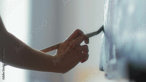 Close-up of the artist's hands holds a brush and paint on canvas oil