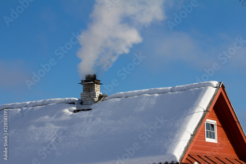 smoke comes from the chimney of a wooden house, a frosty winter