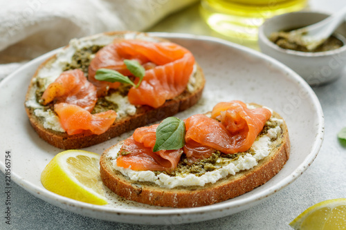 Bread toast with salted salmon, pesto sauce, lemon and cream cheese (ricotta). Gourmet snack. selective focus