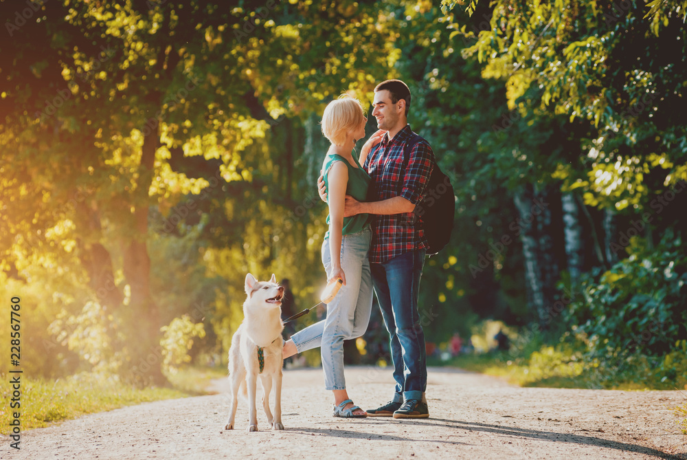 Dog with owners spend a day at the park. Young couple and husky running, playing and having fun. Dog with owners spend a day at the park. Young couple and husky running, playing and having fun.