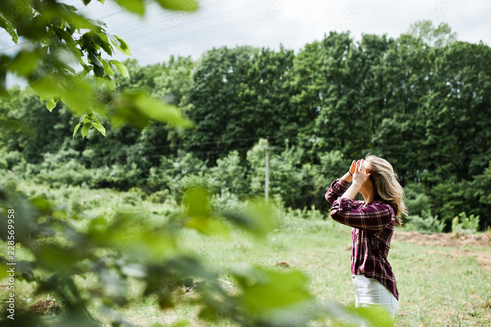 Close-up portrait of a smiling blond girl in tartan shirt in the countryside. Close-up portrait of a smiling blond girl in tartan shirt in the countryside.