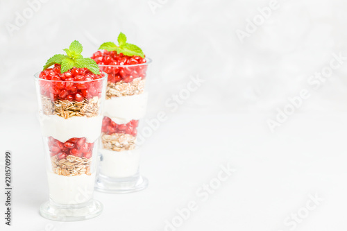 Pomegranate parfait - sweet organic layered dessert with granola flakes, yogurt and ripe fruit seeds.