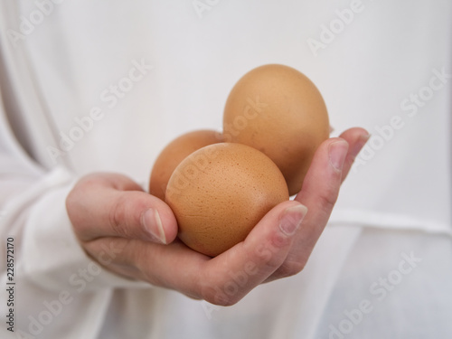 One hand holding three eggs