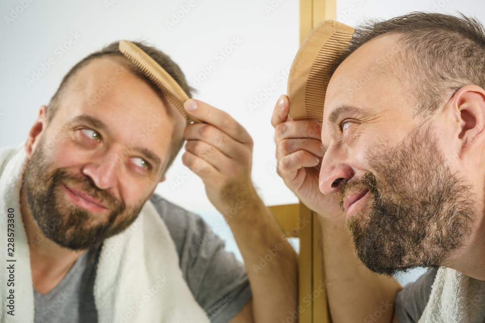 Obraz premium Man using comb in bathroom