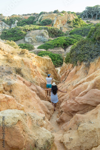 People hiking between the hills of Praia dos Pinheiros in Lagos, Portugal