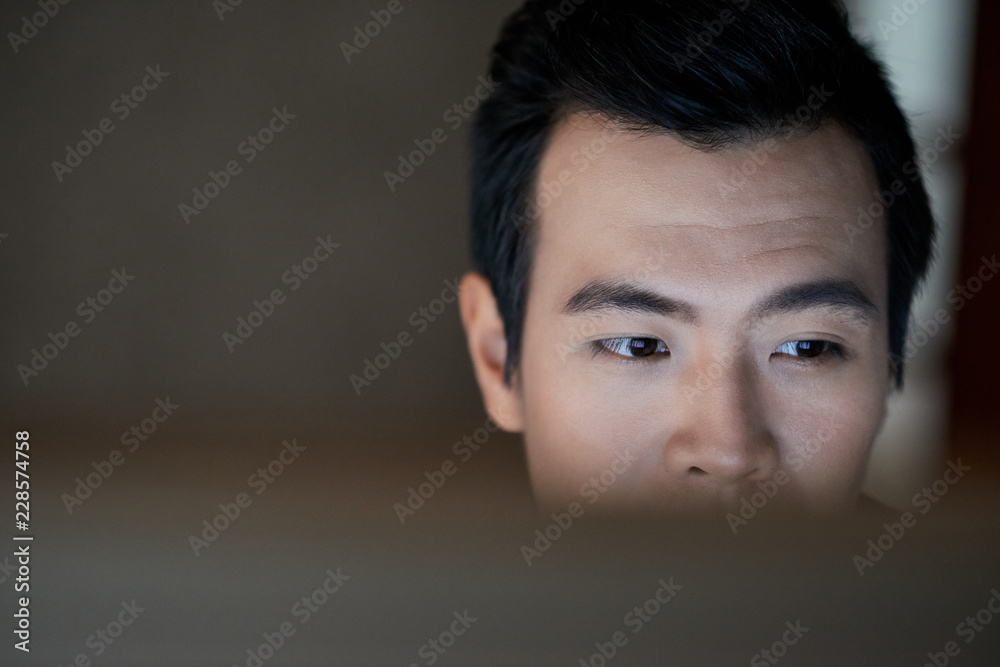 Face of Vietnamese softaware developer checking code on computer screen Face of Vietnamese softaware developer checking code on computer screen