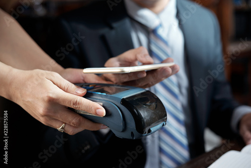 Customer making contactless payment for cup of coffee in restaurant