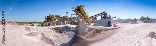 Crushing machinery, cone type rock crusher, conveying crushed granite gravel stone in a quarry open pit mining. Processing plant for crushed stone and gravel. Mining and Quarry mining equipment. photo