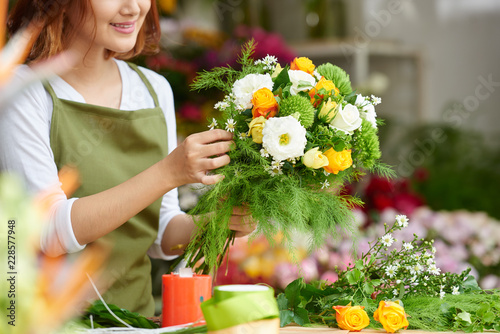 Close-up image of female florist making beautiful bouquet of fresh flowers photo