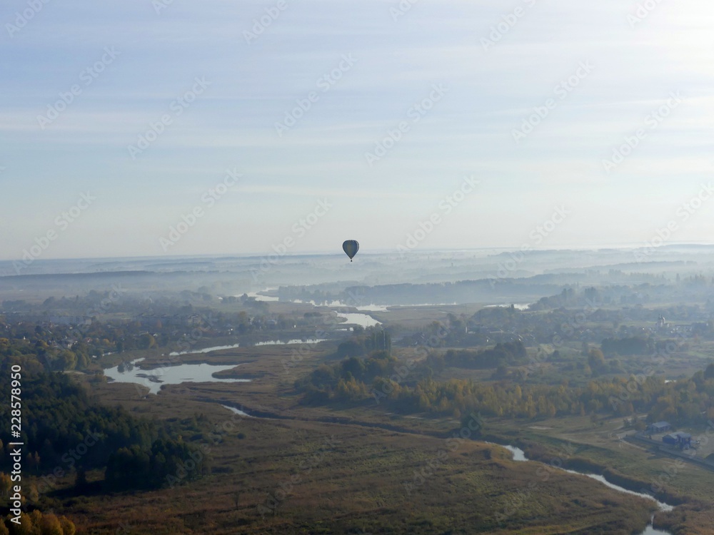 Colorful hot air balloon flying over rock landscape in blue sky Colorful hot air balloon flying over rock landscape in blue sky