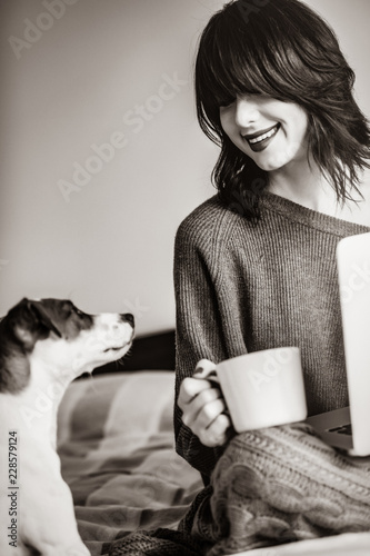 Portrait of a young caucasian woman with of coffee, dog and notebook at home. Image in black and white color photo