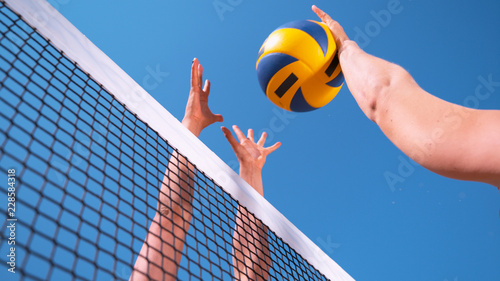 CLOSE UP: Unrecognizable young female' hands playing volleyball at the net. photo