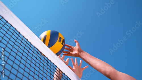 CLOSE UP: Unrecognizable female volleyball player spikes the ball past the block