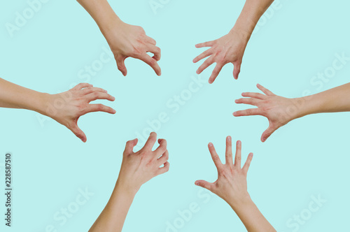 Top view of hands reaching for something isolated on a green, pastel background. The concept of wanting to grab something, gain.