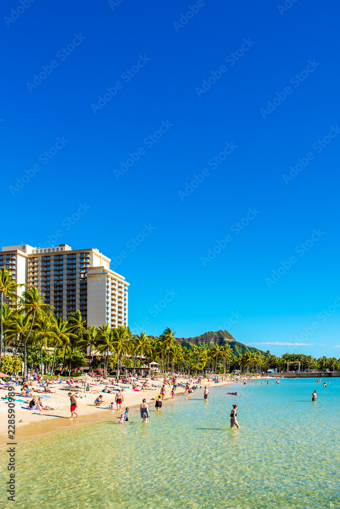 HONOLULU, HAWAII - FEBRUARY 16, 2018: View of the Waikiki beach. Copy space for text. Vertical. HONOLULU, HAWAII - FEBRUARY 16, 2018: View of the Waikiki beach. Copy space for text. Vertical.