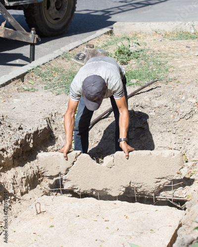 man breaks a concrete slab with iron scrap