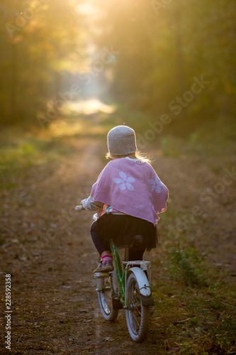 Dziewczynka na rowerze w jesiennym lesie