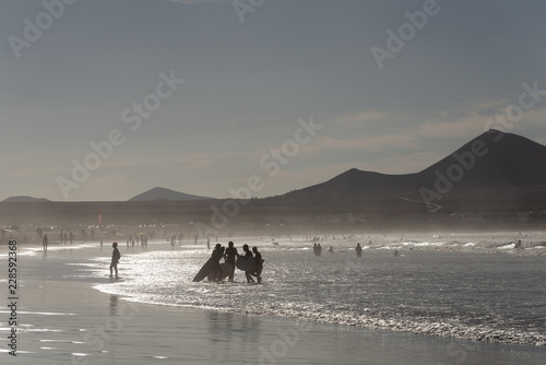 Silhouettes of having a rest on a beach of people in the evening sun in silvery tones