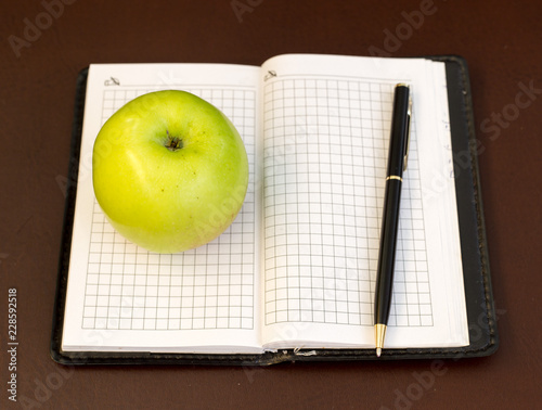 pen and apple on the background of notebook
