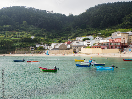 Paisaje de playa con barcas de colores y agua verde y transparente, en Praia da Concha en Lugo, España, verano de 2018 photo