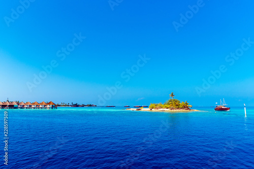 Fototapeta Naklejka Na Ścianę i Meble -  Water bungalow in a raw with turquoise ocean and a island, Maldives. Copy space for text.