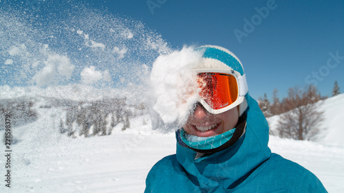 Foto CLOSE UP: Excited girl wearing ski goggles gets hit in the head by snowball