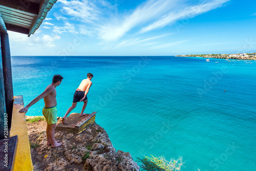 People jump off a cliff, Westpunt, Curacao, Netherlands. Copy space for text.