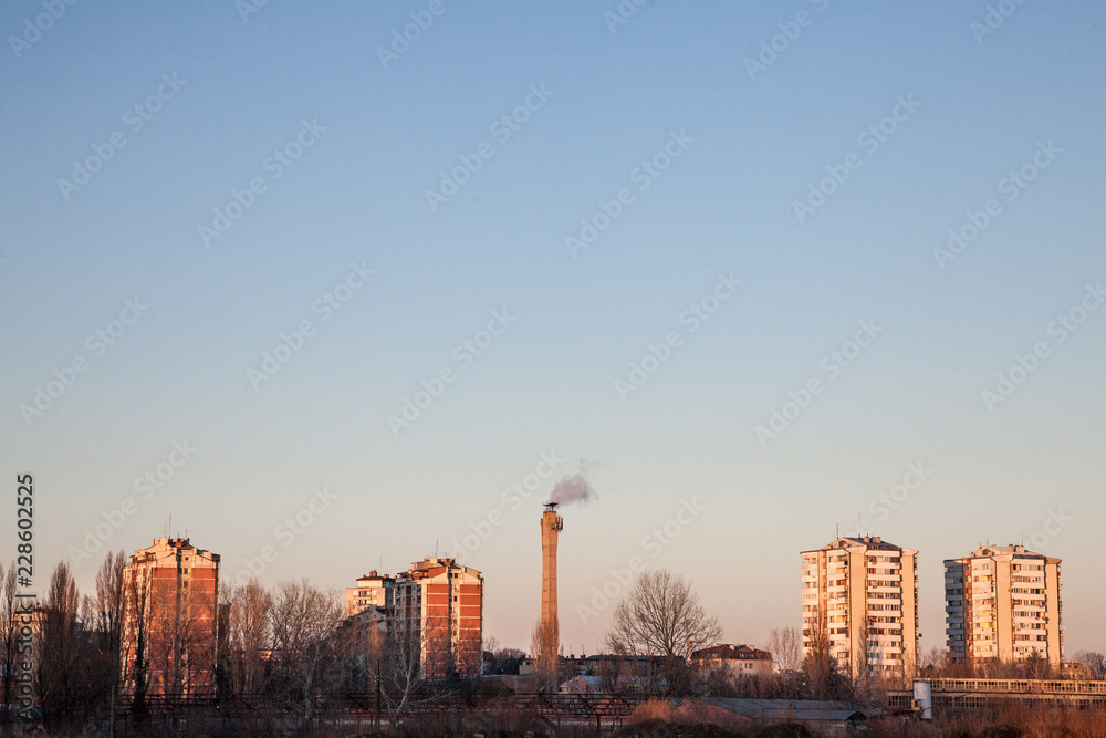 Communist housing buildings facing a polluting chimney smoking & an abandoned factory in Pancevo, Serbia. The towers are a symbol of Socialist architecture and economic transition of Eastern Europe Communist housing buildings facing a polluting chimney smoking & an abandoned factory in Pancevo, Serbia. The towers are a symbol of Socialist architecture and economic transition of Eastern Europe