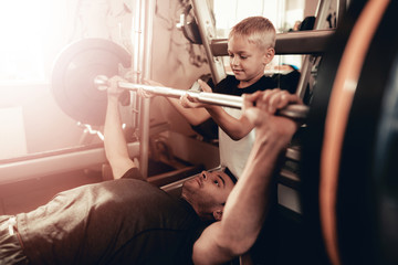 Son Support To Father While Lifting The Barbell.
