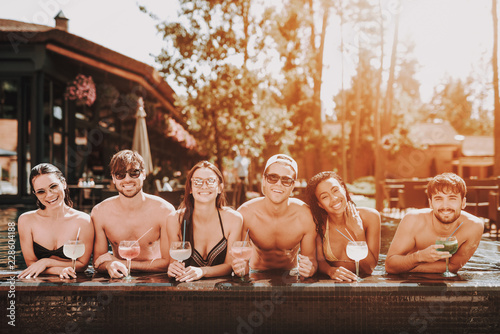 Young Smiling Friends with Cocktails at Poolside