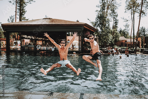 Young Smiling Friends Jumping into Swimming Pool
