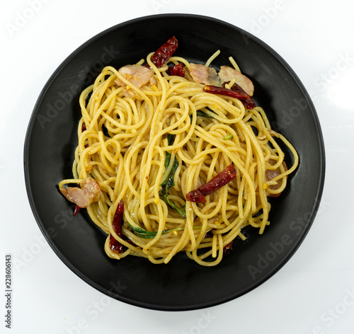 Spaghetti with Dried Chili And Crispy Bacon yellow line in a black dish on white background,Top view,Close up..