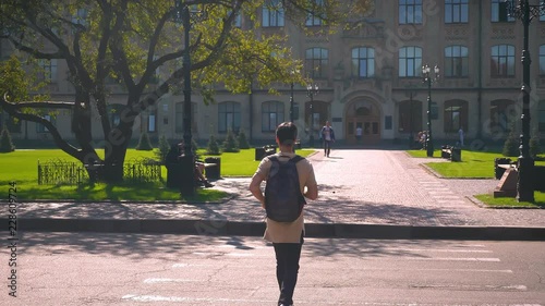 Back shooting of cool asian male, crossing the road at a pedestrian crossing, taking direction to college