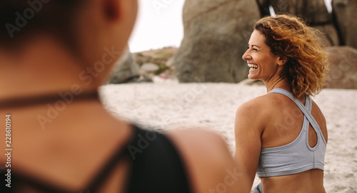Cheerful women in fitness wear sitting on the beach photo